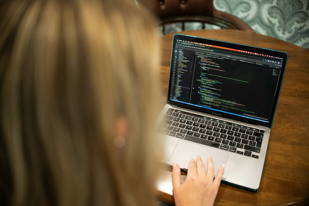 person writing code on laptop